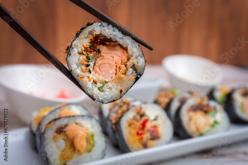 Sushi roll with salmon held on chopsticks