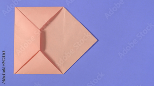 Pink origami envelope on lilac background.