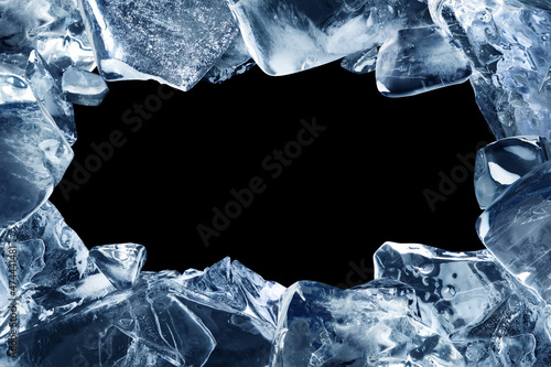 A frame made of broken pieces of ice. Ice chunks with a hole in the middle isolated on a black background. photo