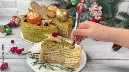 Kid hand taking piece of Xmas honey cake. Christmas cake and decoration on background.