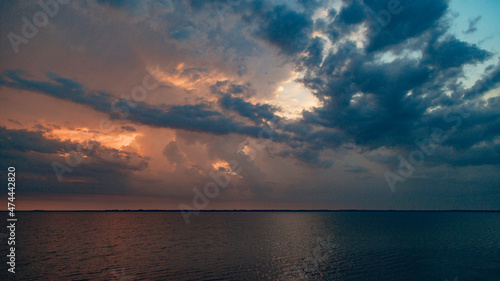 Beautiful Landscape of the Sunset on the Beach. Calm Weather with Dark Clouds in the Golden Sky Reflected in the Water