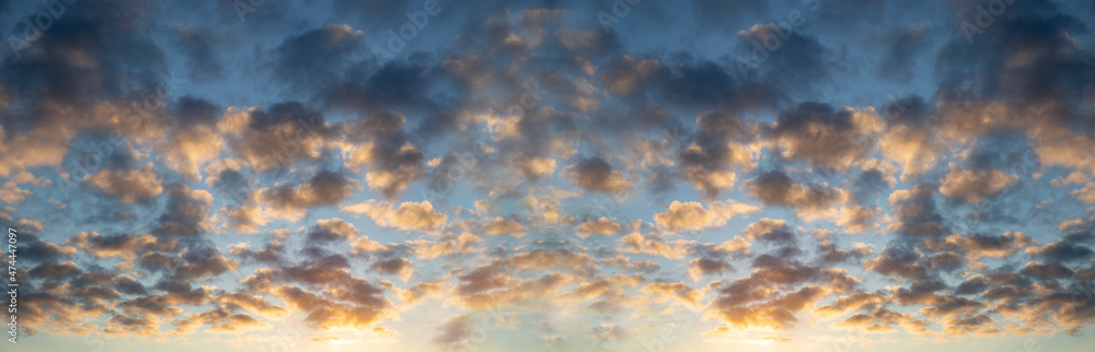 Typical idyllic sky with dense clouds with warm orange colors against a background of blue sky in panorama