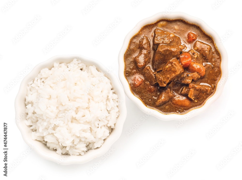 Bowls with tasty beef curry and rice on white background