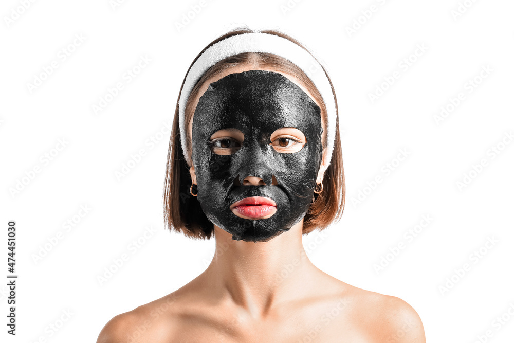 Young woman with activated charcoal mask on her face against white background Young woman with activated charcoal mask on her face against white background