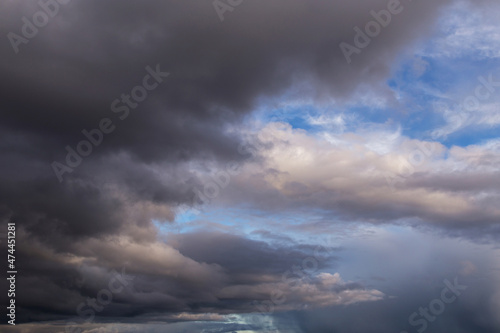 Epic Dramatic storm dark grey cumulus rain clouds against blue sky background texture, thunderstorm. Darkness and light