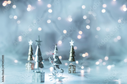 Santa Claus between Christmas trees on festive background with blurred lights