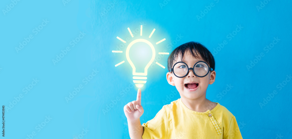 Smart kid nerd asian boy child with light bulb have good idea.Happy student kid thinking creative on blue banner background.Brainstorming and idea concept.online learning imagination innovation.stem. Smart kid nerd asian boy child with light bulb have good idea.Happy student kid thinking creative on blue banner background.Brainstorming and idea concept.online learning imagination innovation.stem.