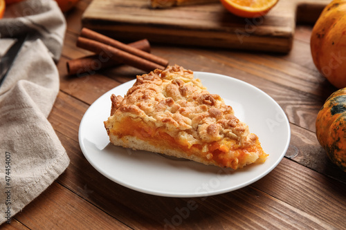 Plate with piece of fresh pumpkin pie on wooden background