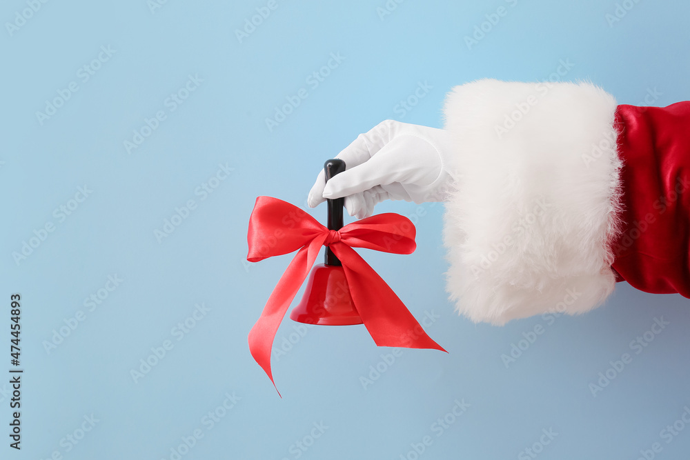 Santa hand with Christmas bell on blue background