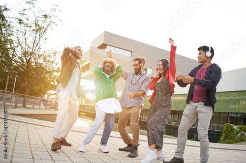 Group of co-workers celebrating.Cheerful People Dancing outdoors at sunset. Young Millennials with headphones listening music. © CarlosBarquero