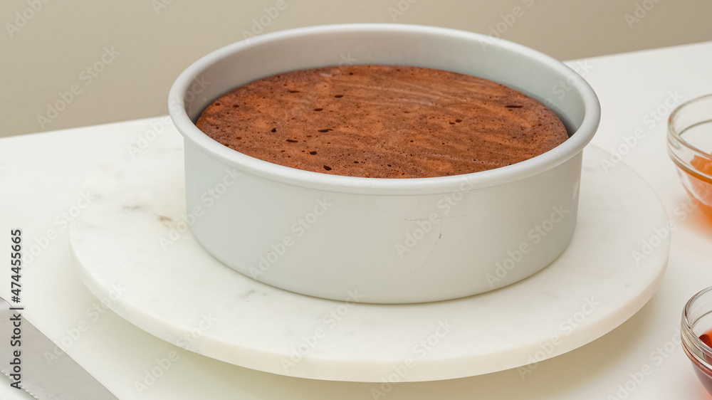 Fresh baked chocolate cake in baking pan, just from the oven, close up view on white kicthen table Fresh baked chocolate cake in baking pan, just from the oven, close up view on white kicthen table