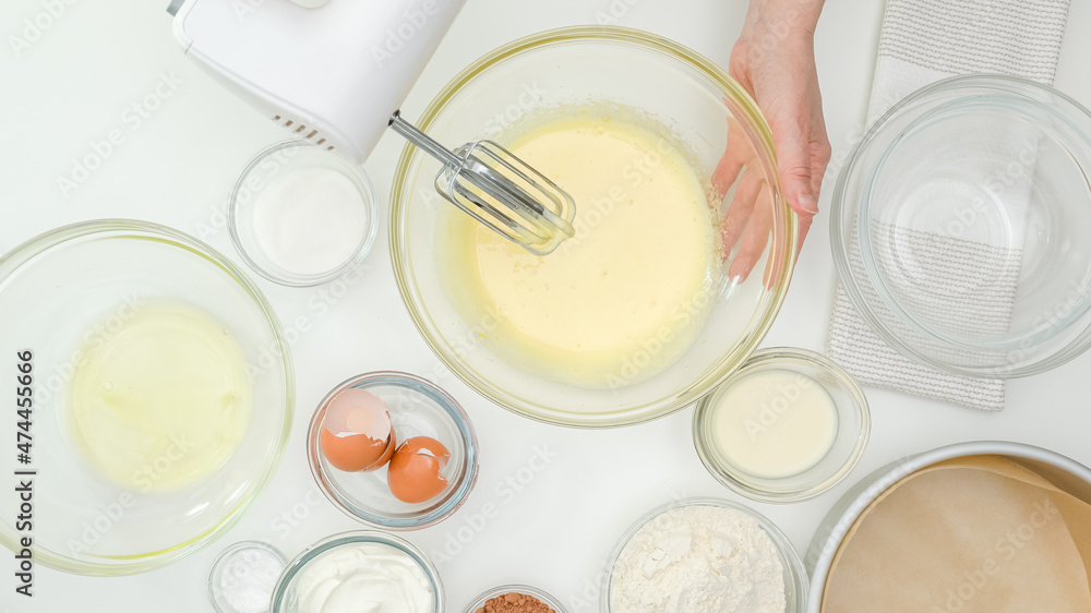 Woman hands mixing egg yolks with sugar in a glass bowl. Close up baking process Woman hands mixing egg yolks with sugar in a glass bowl. Close up baking process