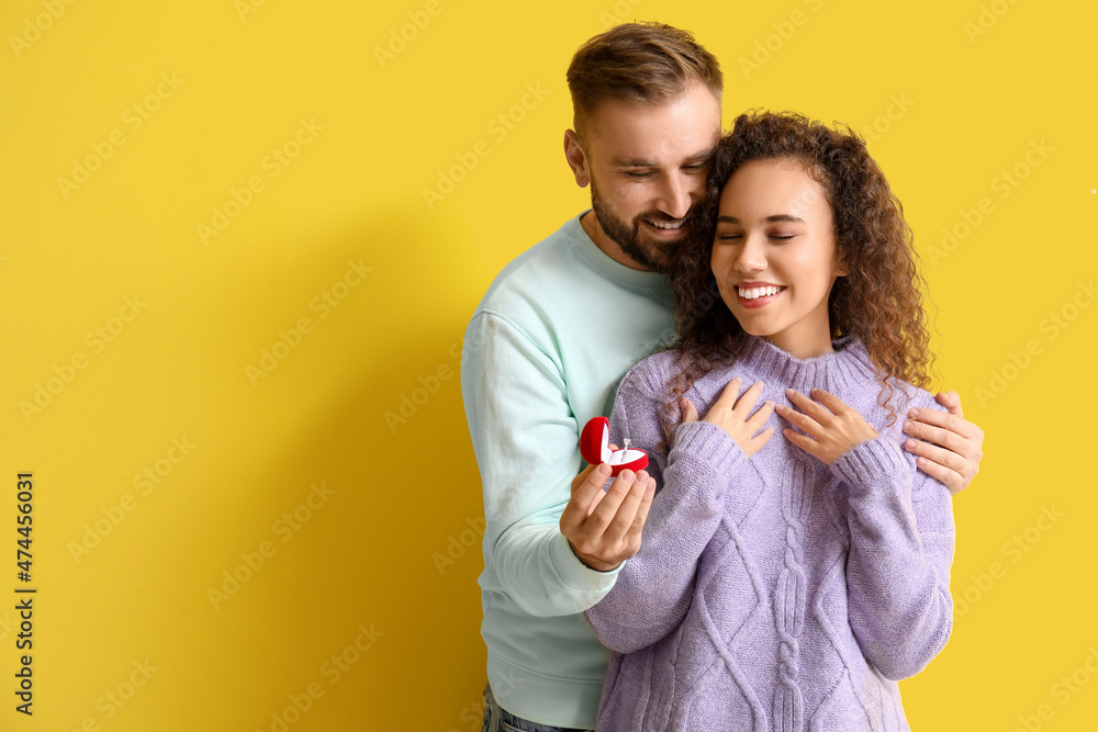 Young man proposing to his girlfriend on color background Young man proposing to his girlfriend on color background