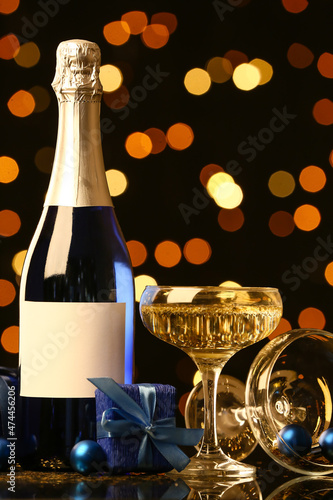 Bottle and glass of champagne with Christmas gift box on table against blurred background