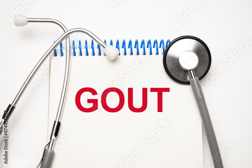 Paper with text GOUT on blue background with stethoscope and pills
