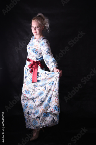 Portrait of a beautiful blonde on a black background in a studio in semi-darkness in a beautiful dress