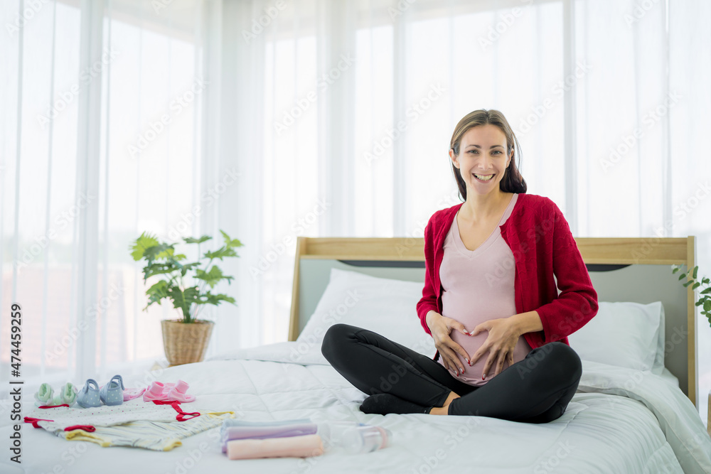 New moms, Europe, Russia sitting on the belly hand made in the shape of a heart on the bed in the bedroom There are baby utensils on the side. Prepare to have a happy child New moms, Europe, Russia sitting on the belly hand made in the shape of a heart on the bed in the bedroom There are baby utensils on the side. Prepare to have a happy child