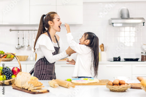 Portrait of enjoy happy love asian family mother and little toddler asian girl daughter child having fun cooking together with dough for homemade bake cookie and cake ingredient on table in kitchen