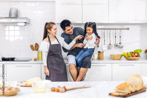 Portrait of enjoy happy love asian family father and mother with little asian girl daughter child play and having fun cooking food together with baking cookie and cake ingredient on kitchen