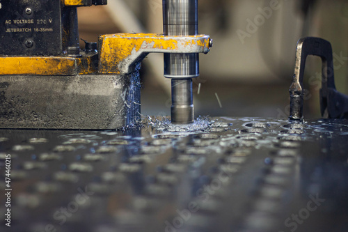 Yellow auger drills holes in steel plates.