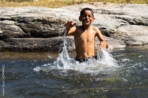 young village boy playing in the river full of water