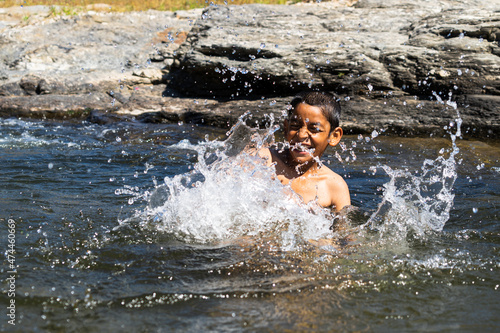 Fototapeta Naklejka Na Ścianę i Meble -  young village boy playing in the river full of water