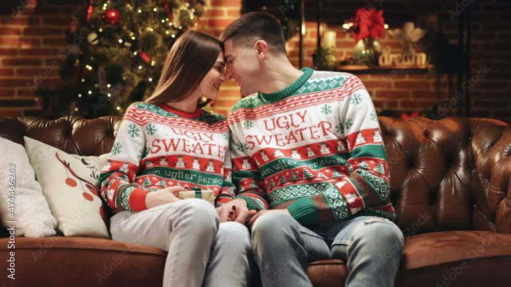 Man gives a present to woman in sweater. Present box wrapped with a green ribbon and paper. Christmas and birthday gifts. Caucasian man giving present to beloved woman on holidays. Family celebration Man gives a present to woman in sweater. Present box wrapped with a green ribbon and paper. Christmas and birthday gifts. Caucasian man giving present to beloved woman on holidays. Family celebration
