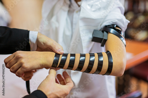 Detail of a moment when a Jewish rabbi puts tefillin on the arm of a thirteen year old boy to say a prayer before the bar mitzvah photo