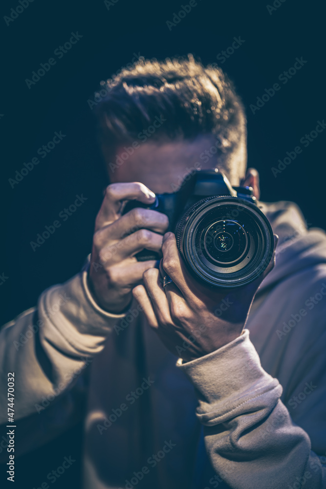 © puhimec - A man photographer with a camera takes a photo in the dark. © puhimec - A man photographer with a camera takes a photo in the dark.