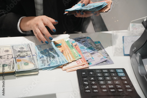 Almaty, Kazakhstan - 11.16.2021 : The bank's cashier recalculates banknotes of different denominations before the exchange