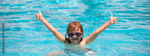 Child raised hands in summer swimming pool. Active kids healthy lifestyle, water sport activity and swimming lessons on summer vacation with child. Banner, copy space. photo