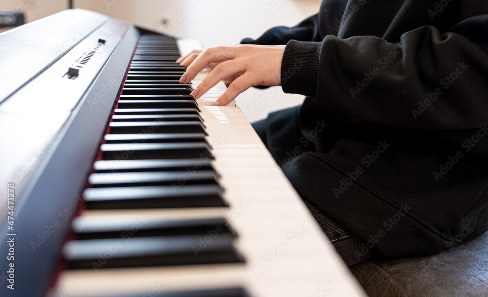 Female hands play musical keys, soft focus.