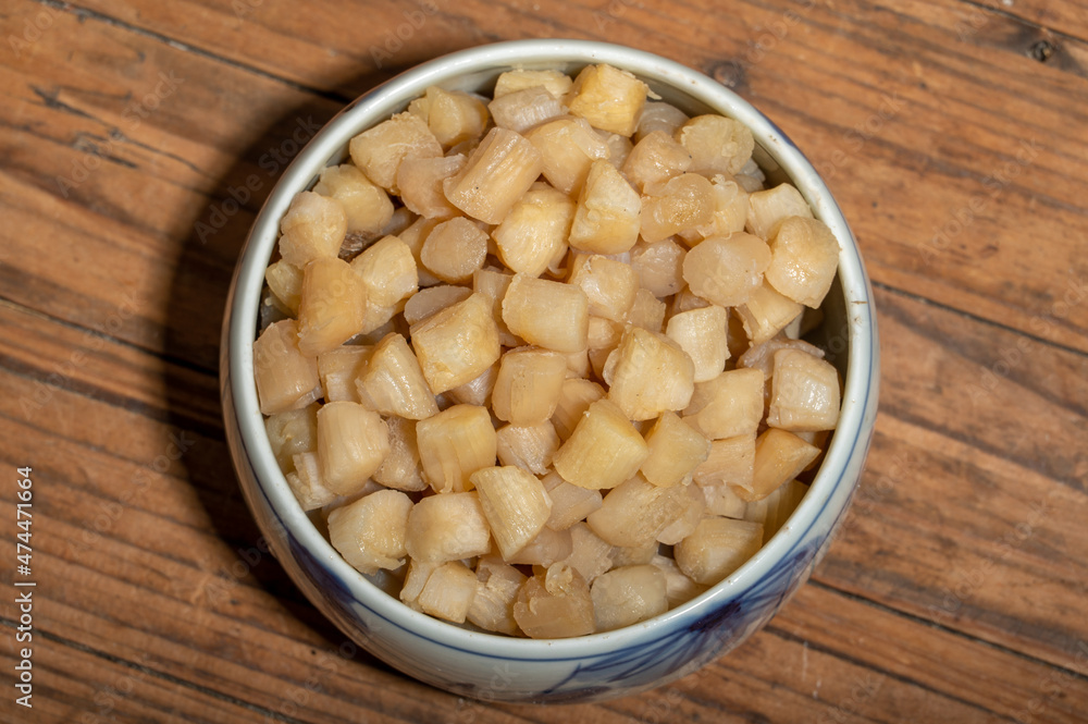 The plates or bowls in the wooden table contain scallops The plates or bowls in the wooden table contain scallops