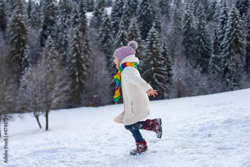 Funny excited child girl running in snow on winter outdoor. Children in winter outdoor in frost snowy day.