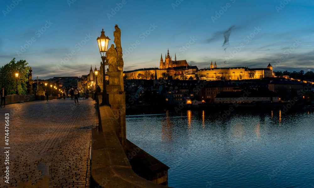 lamp on Charles Bridge on Vltava River and in the background Prague Castle and St. Vitus Cathedral in the center of Prague at sunset in the evening Cer in the early evening