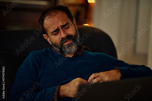 indisposed middle aged man using laptop at home