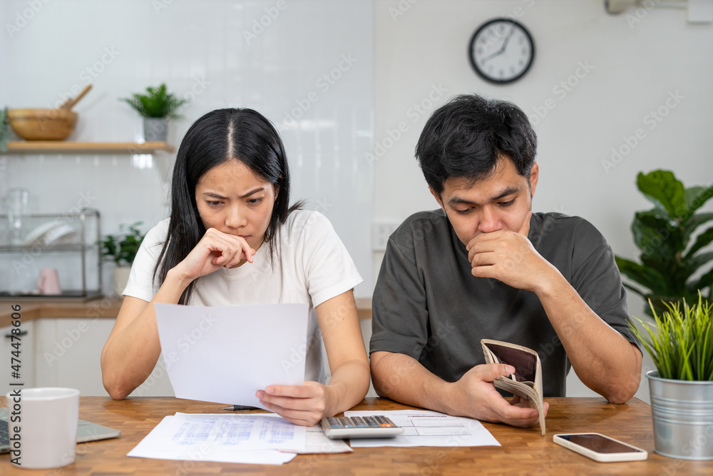 Asian couples are worried about debt and expenses. Stressful women and men receive bank loan invoices. credit card , water, electricity , telephone bills. No money and broke Asian couples are worried about debt and expenses. Stressful women and men receive bank loan invoices. credit card , water, electricity , telephone bills. No money and broke