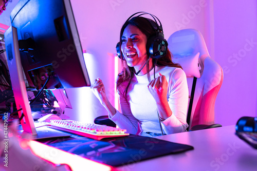 young  playing game online at home. Gamer  controlling joystick for video game. Teenage girls leisure game in neon light room at home. photo