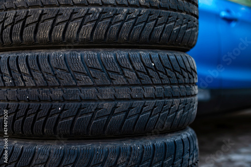 winter tires next to the car in wheel service, seasonal tire change concept, close-up