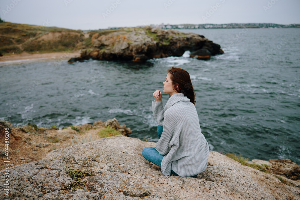 woman seated on the coast sweater landscape female relaxing