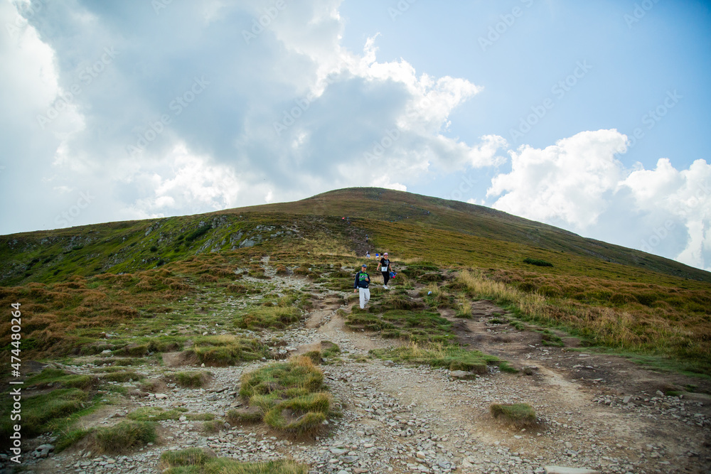 People descend down a large green mountain range. Mountain Hiking People descend down a large green mountain range. Mountain Hiking