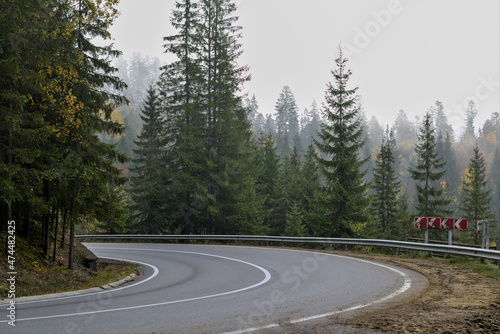 Landscape with a foggy mountain road passing through a magical forest. Nature background. Dangerous turn on the road in the Ukrainian Carpathians.