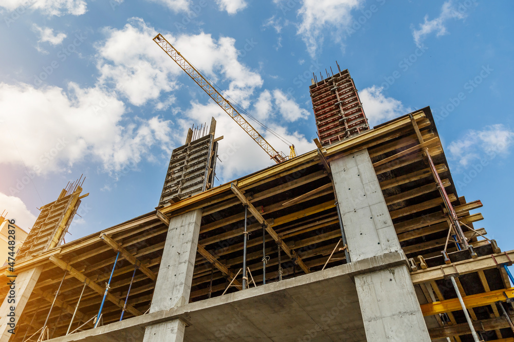 Obraz premium Extensive scaffolding providing platforms for work in progress on a new apartment block,Tall building under construction with scaffolds,Freestanding tower crane on a building site