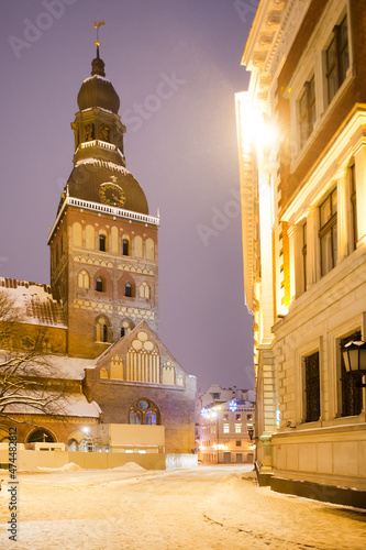 Winter evening on the main square of the city  street by evening lights  before Christmas  New Year. Christmas Fair. Catholic cathedral  church  tower. Riga  Latvia.