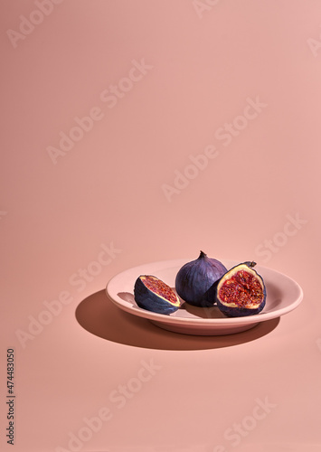 Contemporary still life with figs on pink background with strong shadows
