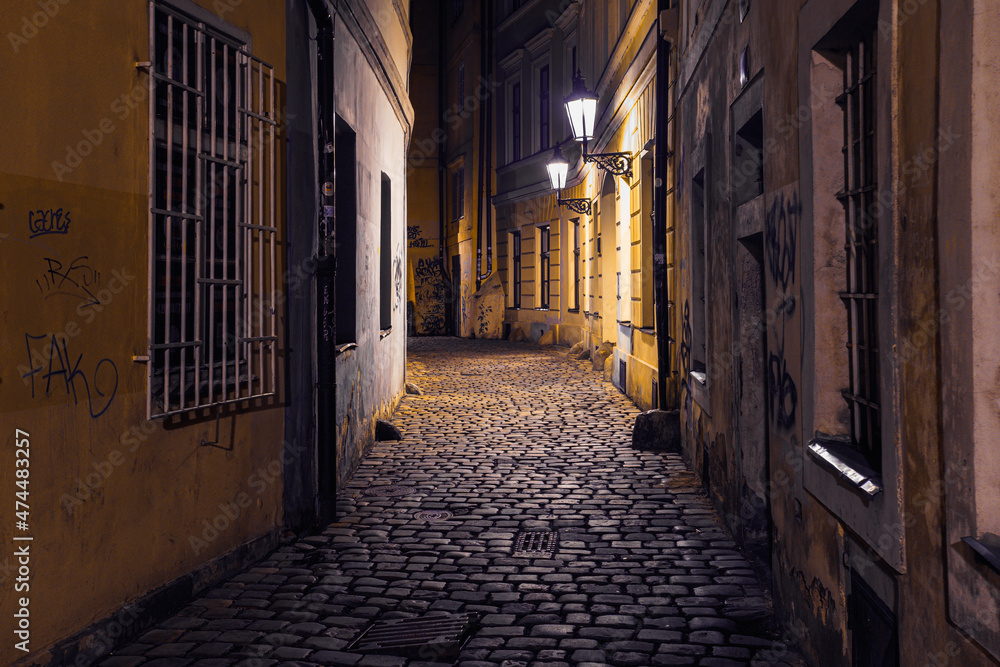 Obraz premium view of a dark and illuminated cobblestone street in the old town of prague at night 2021