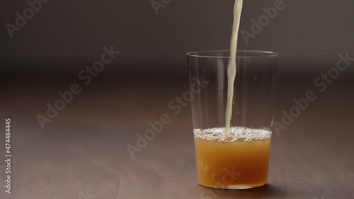 pour orange detox drink into tumbler glass on wood table