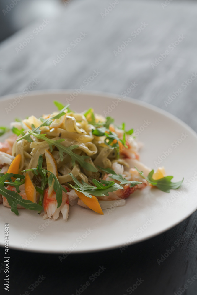 Fettuccine pasta with crab and arugula on black wood table