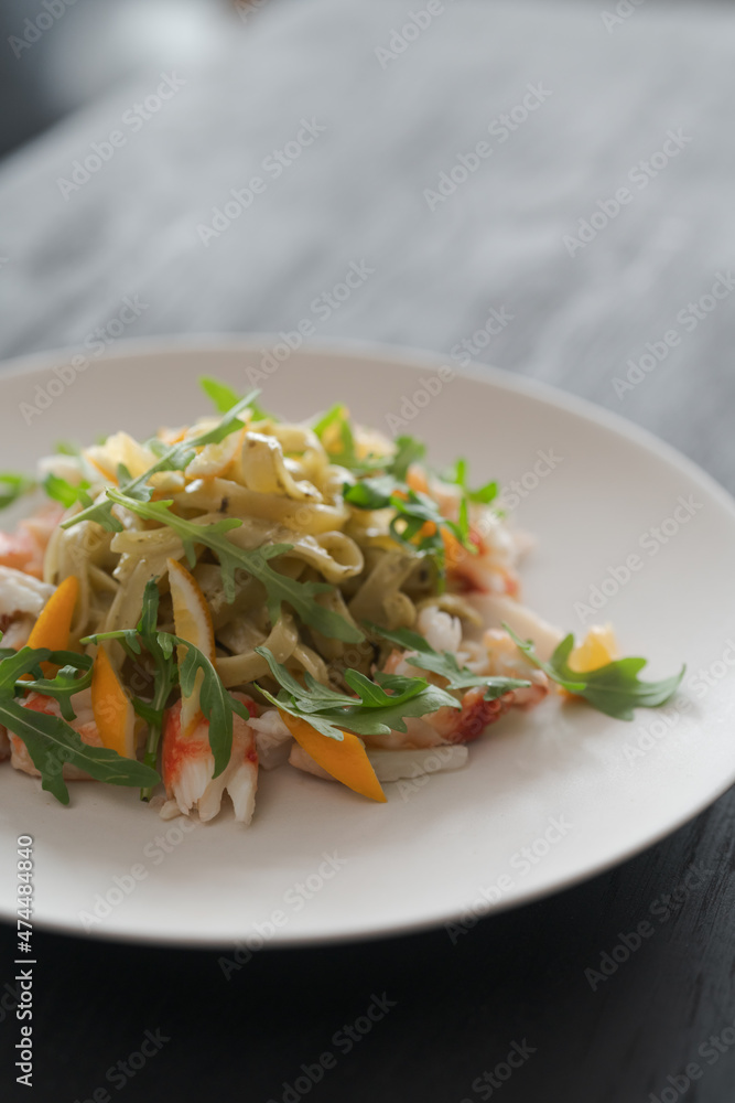 Fettuccine pasta with crab and arugula on black wood table Fettuccine pasta with crab and arugula on black wood table