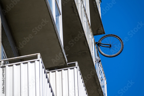 Bicycle wheel protruding from balcony of multi-storey building, view from below. photo